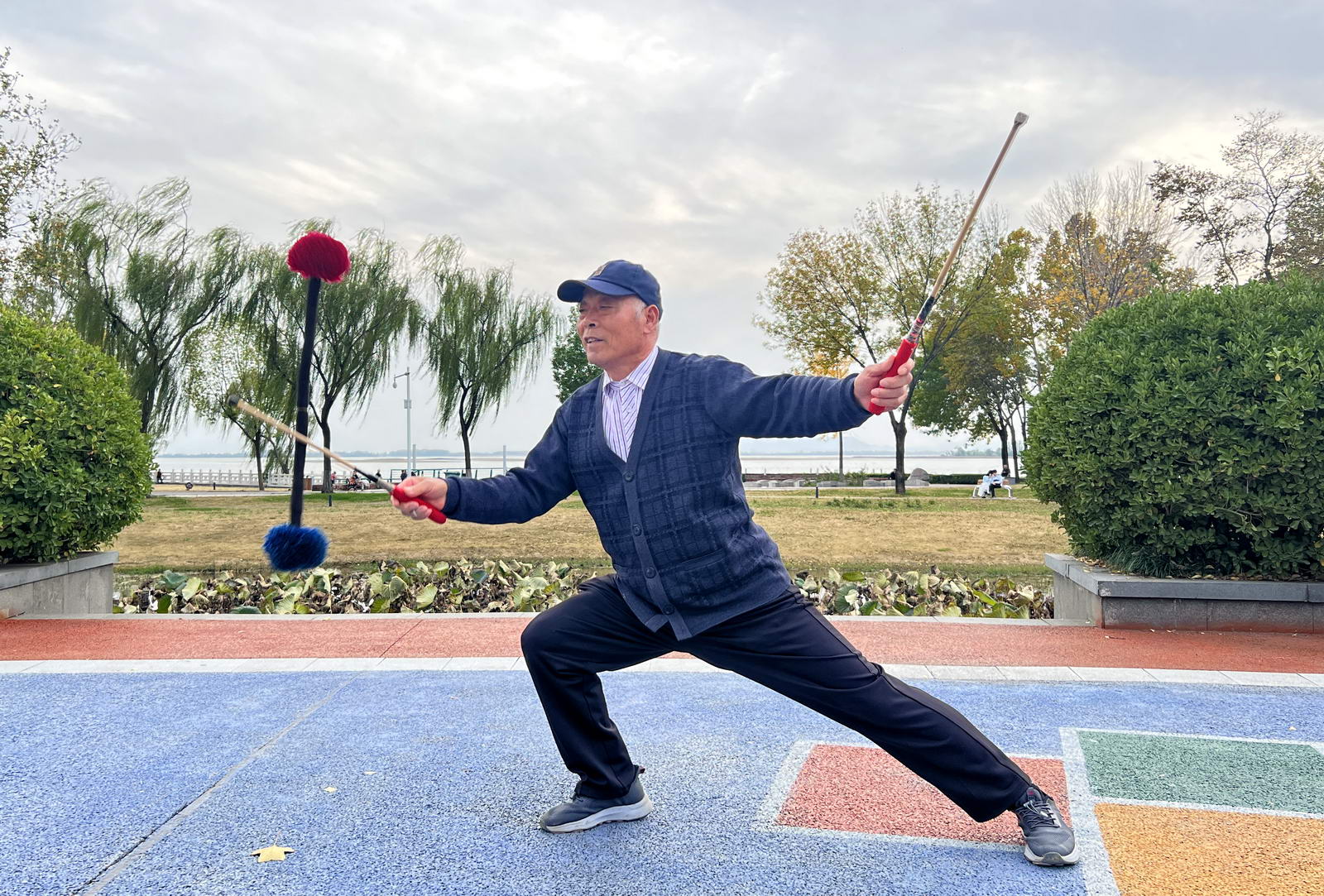 边青坡今年71岁。是位快乐的＂小青年＂。兴趣广泛，盆景、地书、打乒乓球、唱歌样样都行。对打花棍活动情有独钟，他的花棍＂举火冲天＂、＂静侯佳音“、＂仙人指路＂小花样，引人注目叫绝。摄影：王仲平